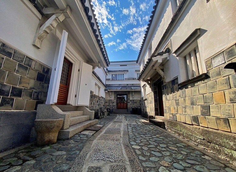 A traditional Japanese alleyway with stone paving and white buildings. 5