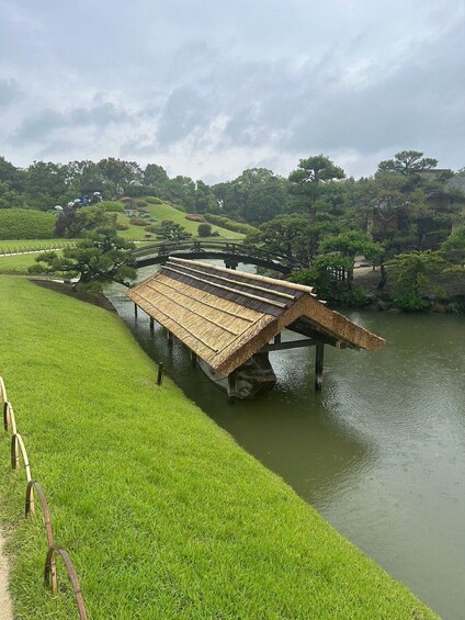 A traditional wooden bridge over a calm river, surrounded by lush greenery and trees. 3