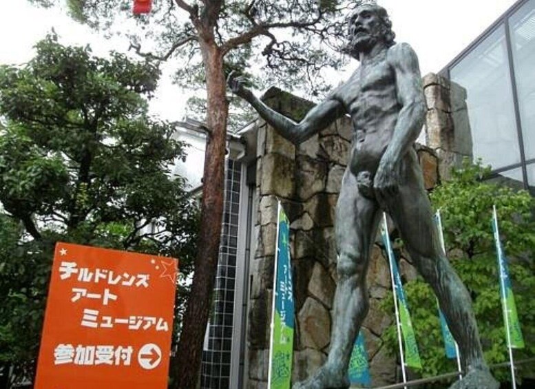 A statue of a muscular figure in a dynamic pose, set against a stone wall and trees. 4
