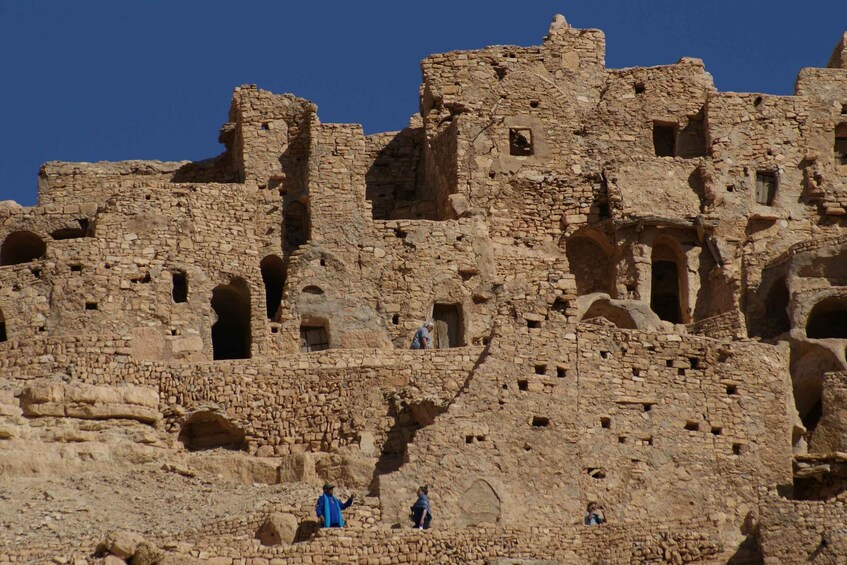 Alte Steinruinen mit mehreren Rundbögen und einer Person, die eine Treppe hinaufsteigt. 3