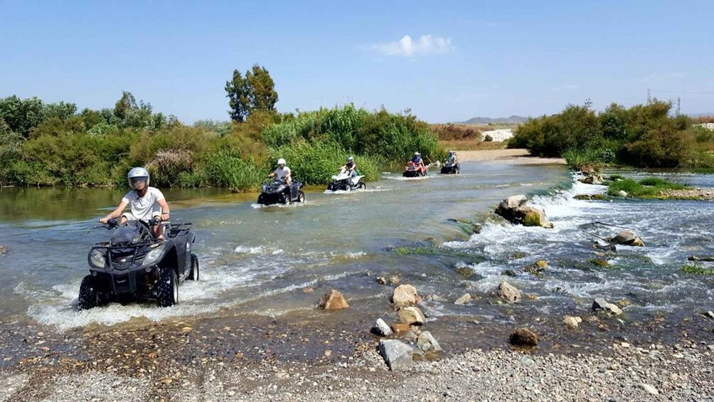 People riding all-terrain vehicles on a river. 3