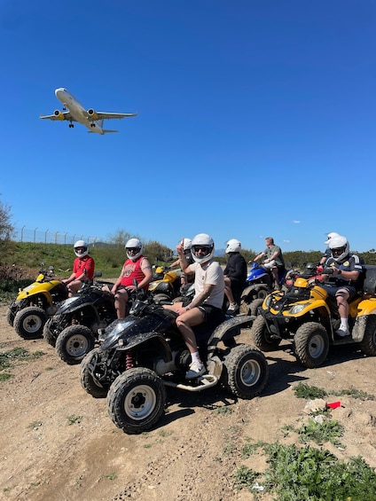 People on ATVs with an airplane flying in the background. 1