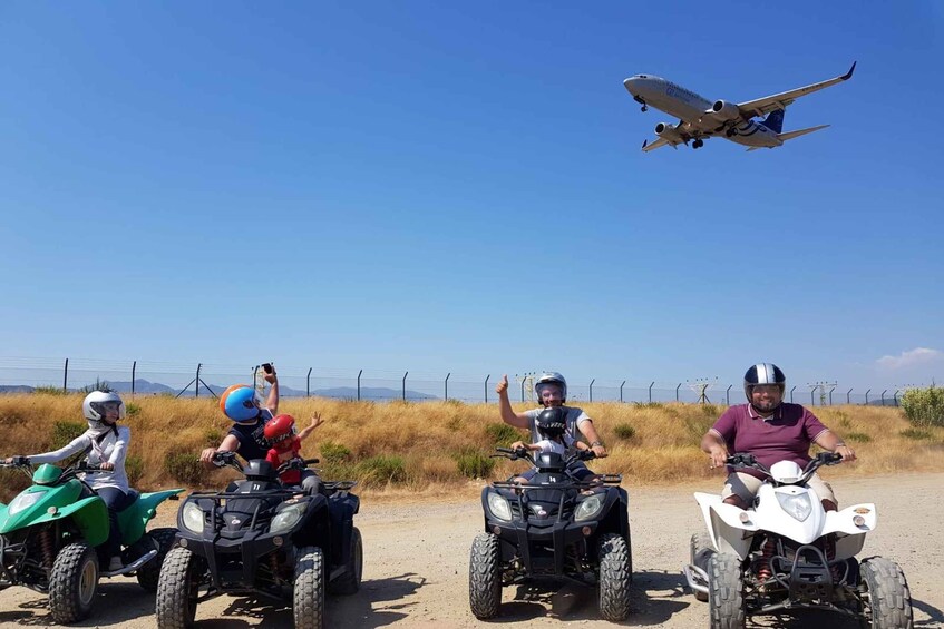 Four people on ATVs with a plane in the sky. 3