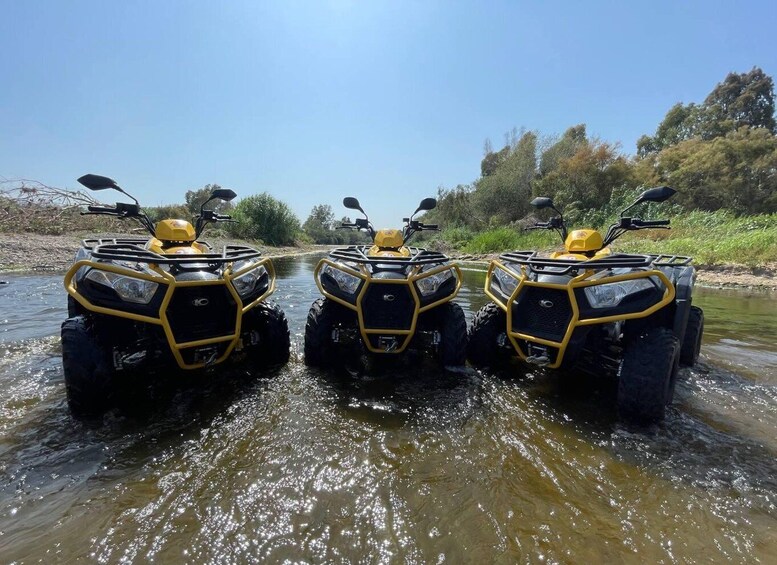 Three yellow quad bikes crossing a shallow river. 2