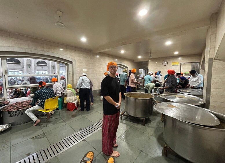 A busy kitchen with people preparing food, large pots, and a person standing in the center. 3