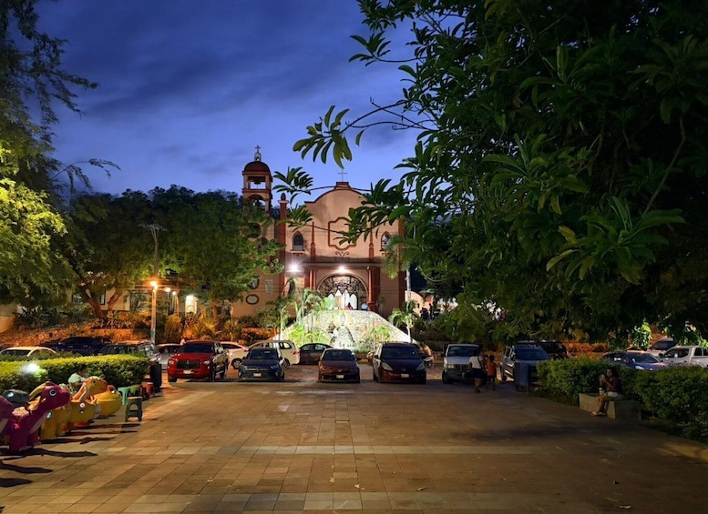 A church with a bell tower, surrounded by parked cars and illuminated by street lamps. 3