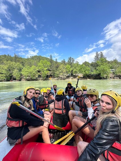 A group of people in a raft on a river surrounded by trees. 1