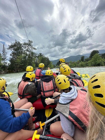 A group of people rafting on a river, wearing helmets and life jackets. 3