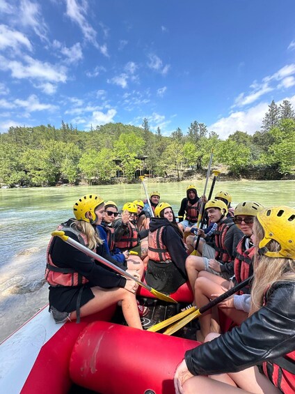 A group of people in a red raft on a river, wearing helmets and life jackets. 2
