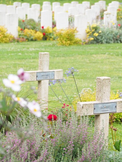 A cemetery with headstones and flowers. 2