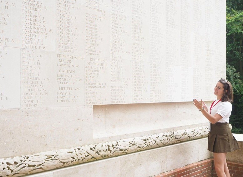 A person standing in front of a large memorial wall with names inscribed. 3