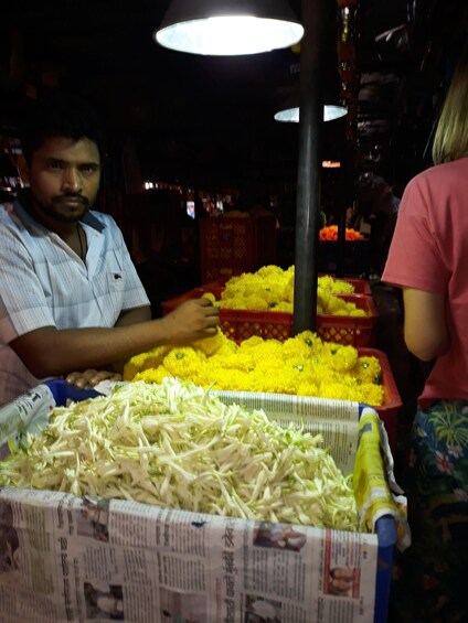 A person arranging yellow flowers and white vegetables in a market setting. 4