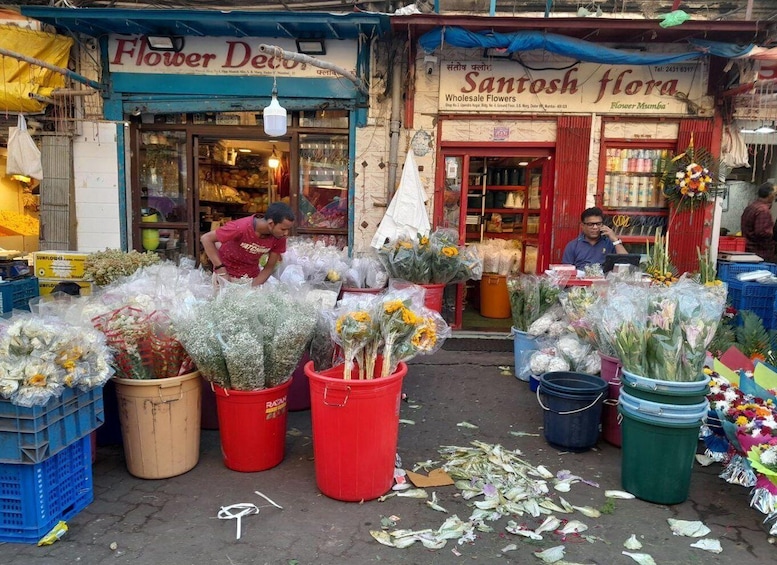 A flower market with various flowers displayed in buckets and crates. 2