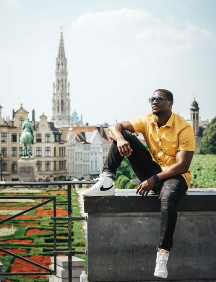 A person sitting on a concrete ledge with a cityscape in the background. 4