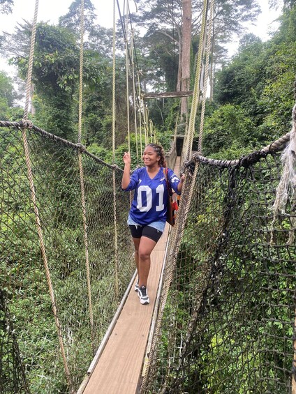 A person running on a rope bridge surrounded by dense greenery. 5