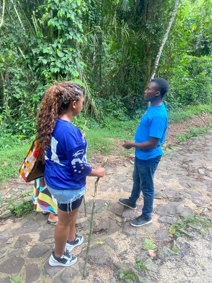 Two people standing on a stone path in a forested area. 3