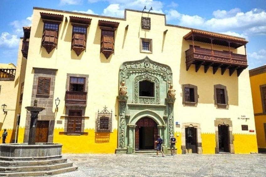 A historic building with a green ornate entrance, yellow walls, and brown shutters. 4