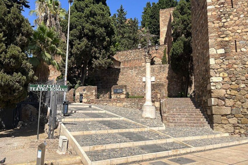 A stone staircase leading to a theater entrance, surrounded by trees and a stone wall. 2
