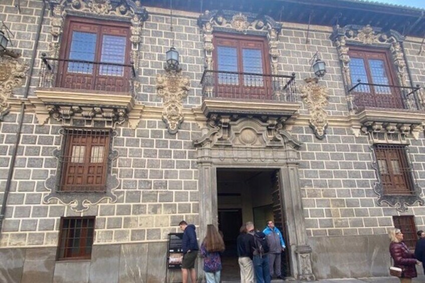 Een historisch gebouw met versierde architecturale details, waaronder decoratieve ramen en een statig entree. 2