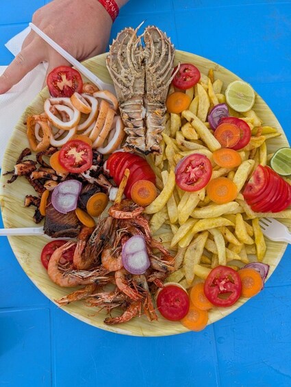 A seafood platter with shrimp, octopus, fish, and fries on a wooden plate. 4