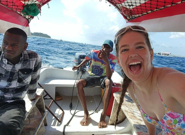 Three people on a boat with a net canopy, in open water. 2