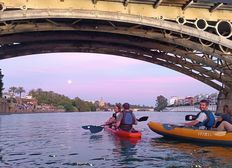 Kayakers under a bridge with a sunset in the background. 1