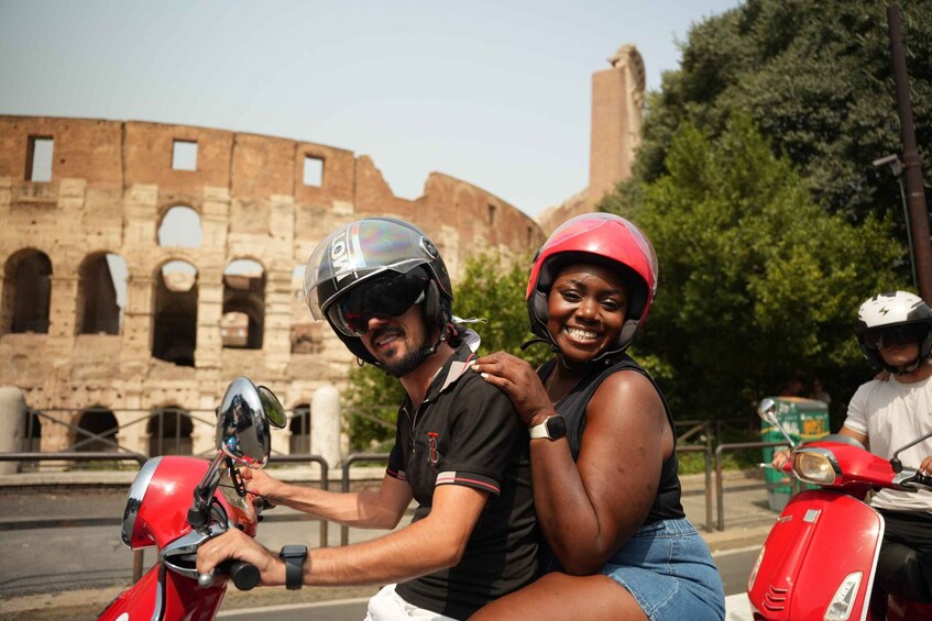A person riding a red scooter with a historic coliseum in the background. 2