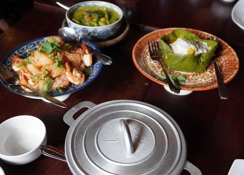 A table with various dishes, including a bowl of soup, a plate with a wrapped item, and a dish with seafood. 5