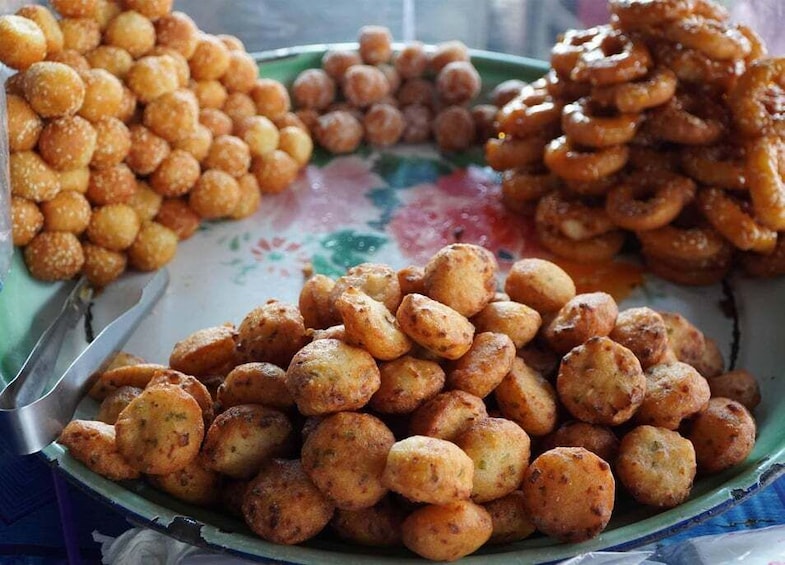 A plate of assorted fried snacks, including fritters and possibly some doughnuts. 2