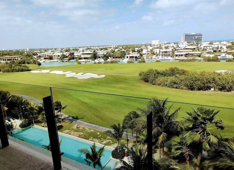 A golf course with a swimming pool, palm trees, and a cityscape in the background. 3