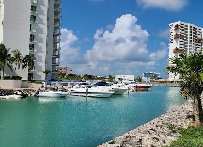 A marina with several yachts docked, a tall building, and a clear blue sky. 5