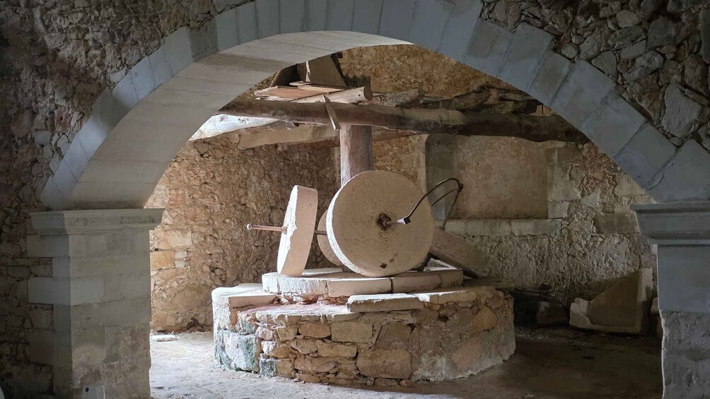 An ancient stone structure with a large wheel and wooden beams. 3