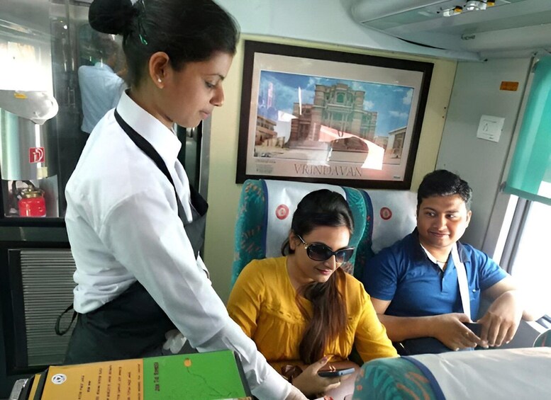 A train interior with passengers, a framed picture of a building, and a vending machine. 2