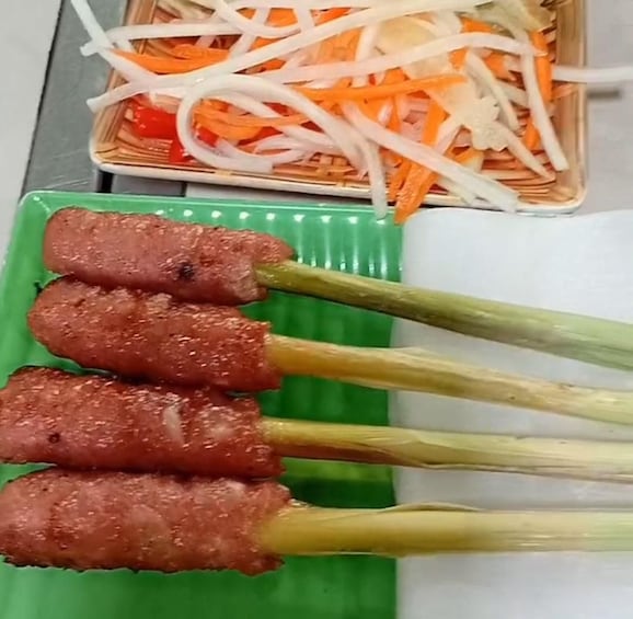 Skewers of grilled meat on skewers, a plate of sliced vegetables, and a green plate with a white napkin. 3