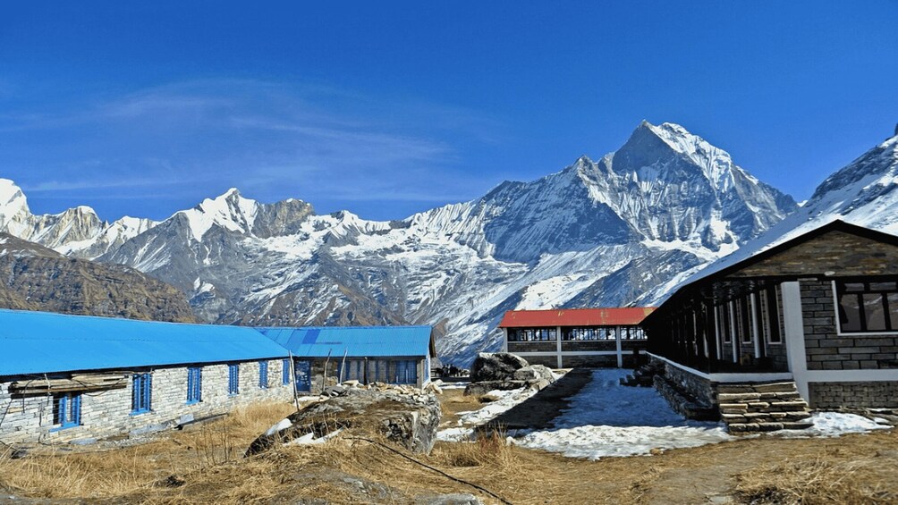 Paesaggio montuoso con cime innevate, un edificio con tetto blu e un edificio con tetto rosso. 3