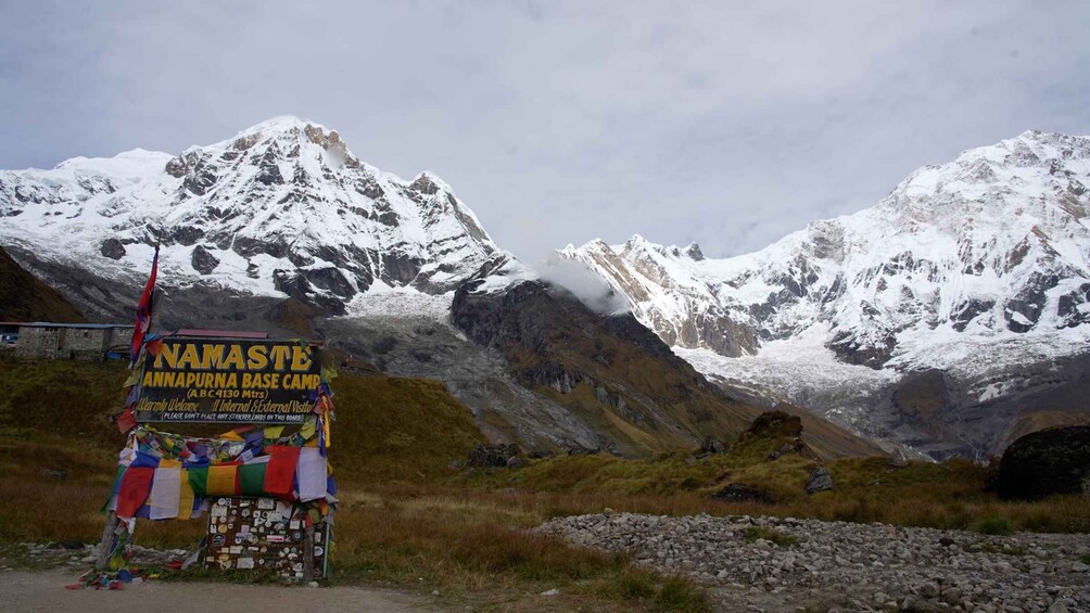 Segnaletica per Namaste Annapurna Base Camp con montagne innevate sullo sfondo. 1