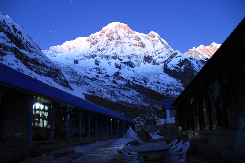 Una montagna innevata al crepuscolo, con un edificio in primo piano. 4