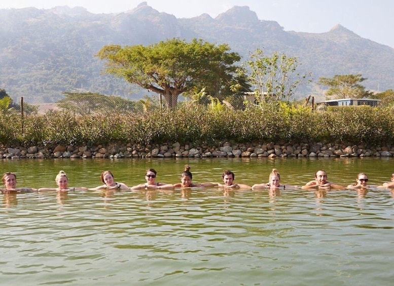 A group of people swimming in a natural pool surrounded by trees and mountains. 3