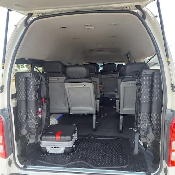 The back of a white van with a black luggage compartment and a suitcase. 2
