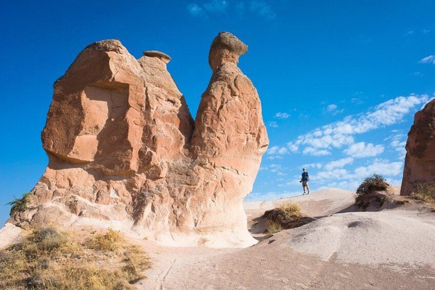 A person standing on a sandy path with rock formations in the background. 4