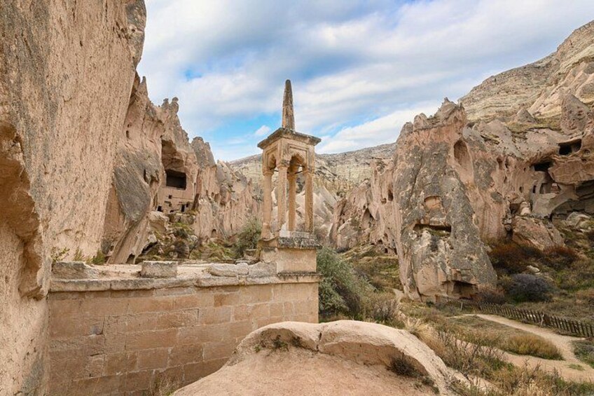 A rock-cut church with a central dome and arches, surrounded by rugged, eroded rock formations. 5