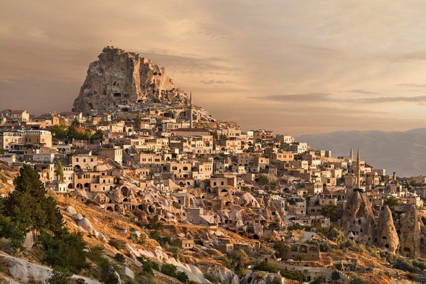 A town with a prominent rocky hill, numerous buildings, and a mosque. 2