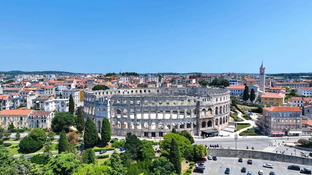 A historic amphitheater surrounded by urban buildings and greenery. 3