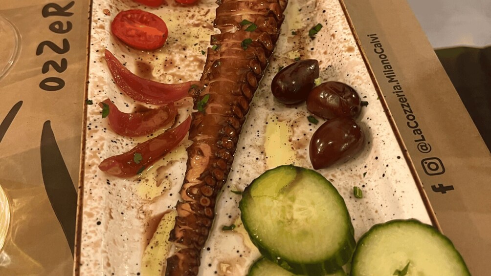 A dish with octopus, tomatoes, olives, and cucumber slices. 2