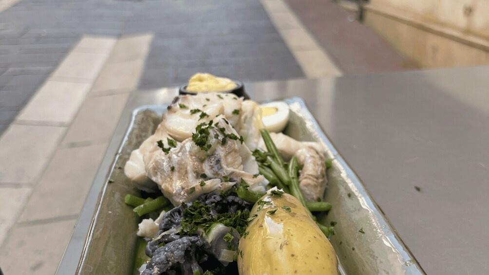 A meal with chicken, green beans, and a boiled egg in a metal container. 3