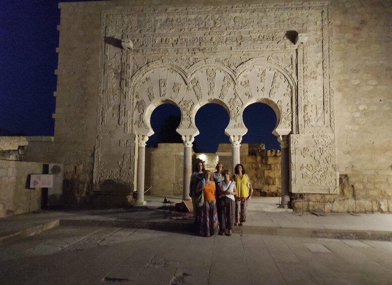 A group of people standing in front of a historic building with ornate arches and detailed carvings. 4