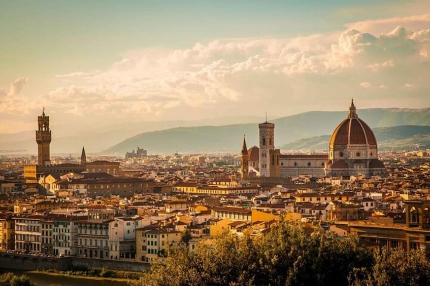 A panoramic view of a city with prominent historical architecture, including a large dome and towers, set against a backdrop of mountains and a clear sky. 1