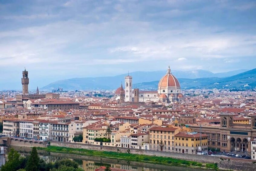 A panoramic view of a city with a prominent dome and tower, surrounded by a river and mountains in the background. 4