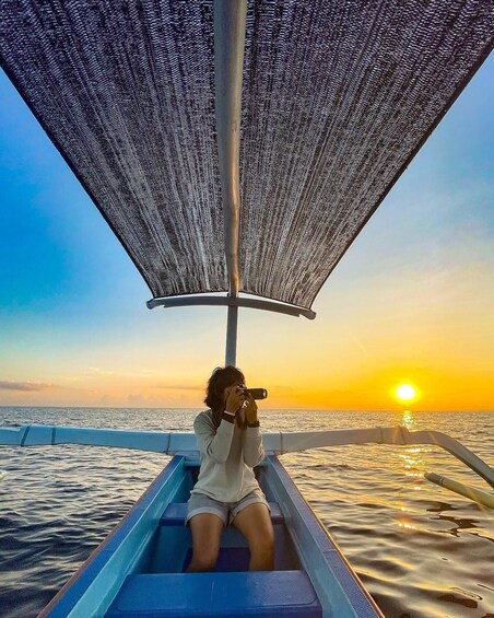 A person in a boat taking a photo of the sunset. 1