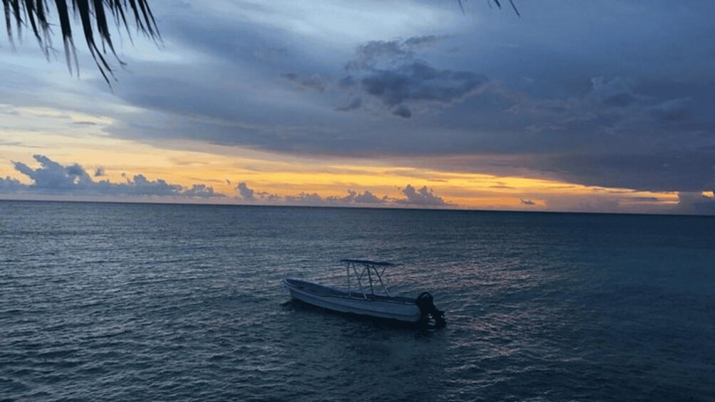 A calm sea with a boat anchored near the shore during sunset. 2